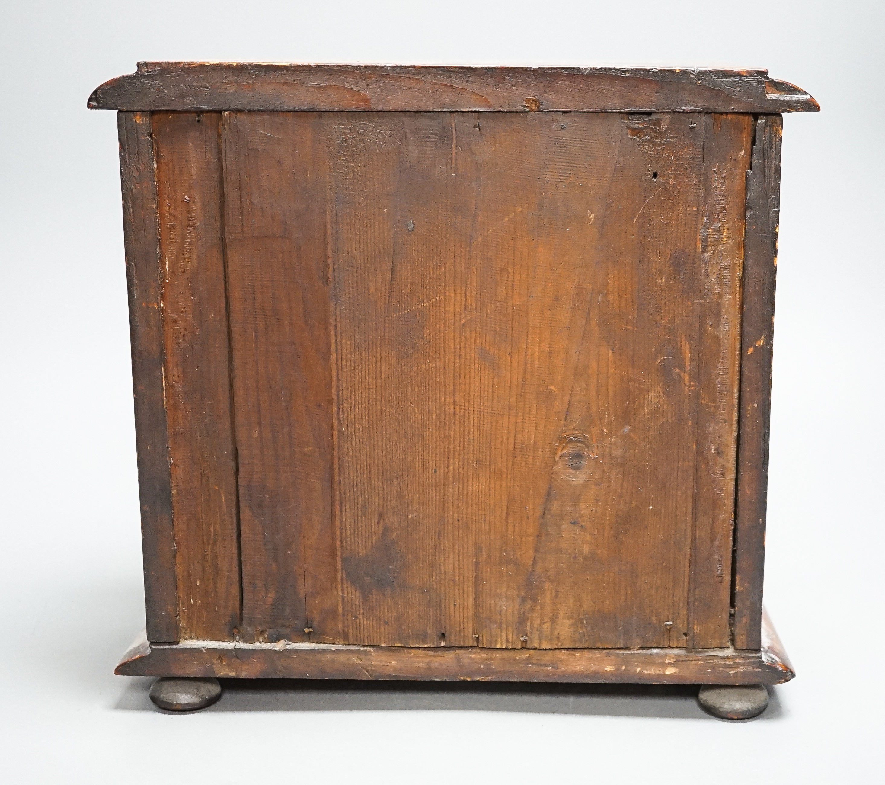 A Victorian stained pine miniature chest of drawers, 27 cms high.